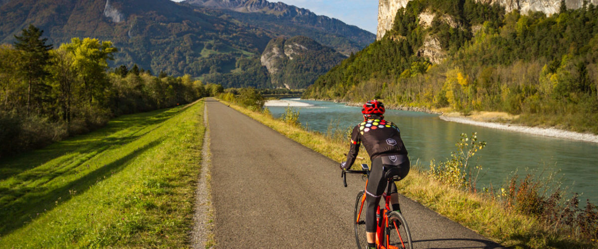 One male cyclist riding along the Rhine river in Kanton Grabünden, Switzerland
